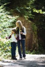 Mother and daughter walking on a road in the forest